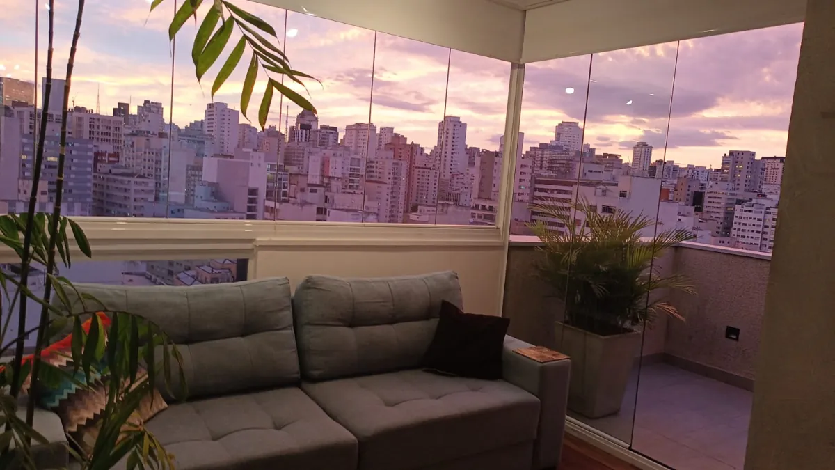 Sofá da varanda do apartamento em Higienópolis com o céu lilás no fim da tarde